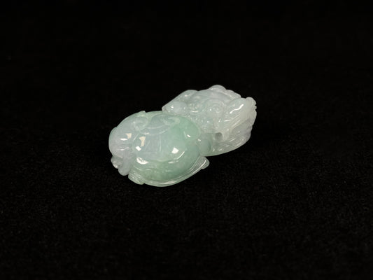 A Pi Xiu jadeite carving with a light green lower body and creamy white head.