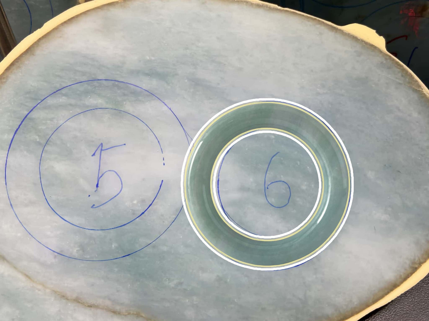 Circular patterns with numbers drawn on a textured surface. Multi-purpose Carving of Jadeite Rough Stones & Custom Bangle Services