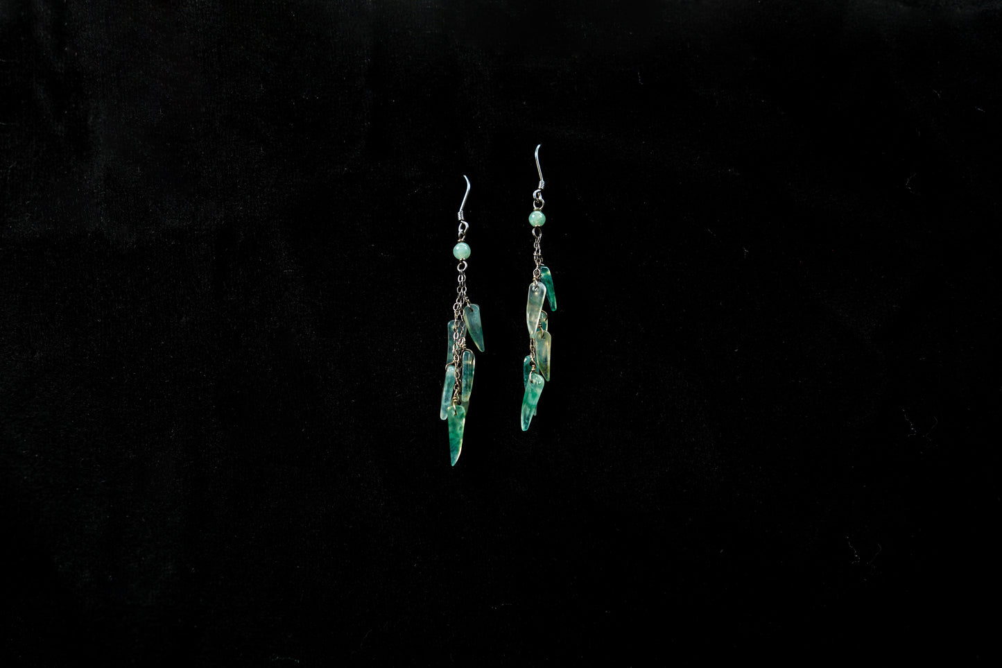 Pair of green earrings on a black background
