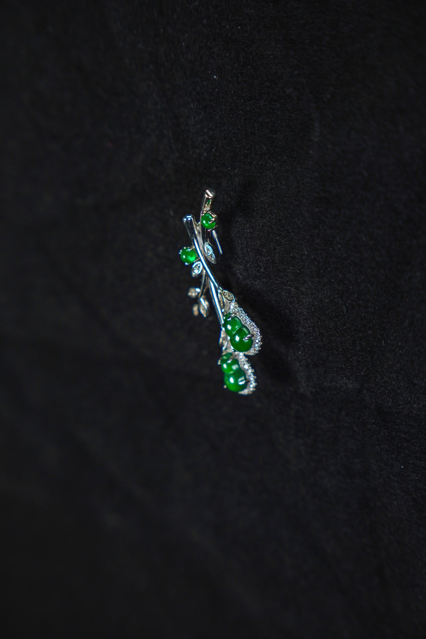 Silver pendant with green gemstones on a black background