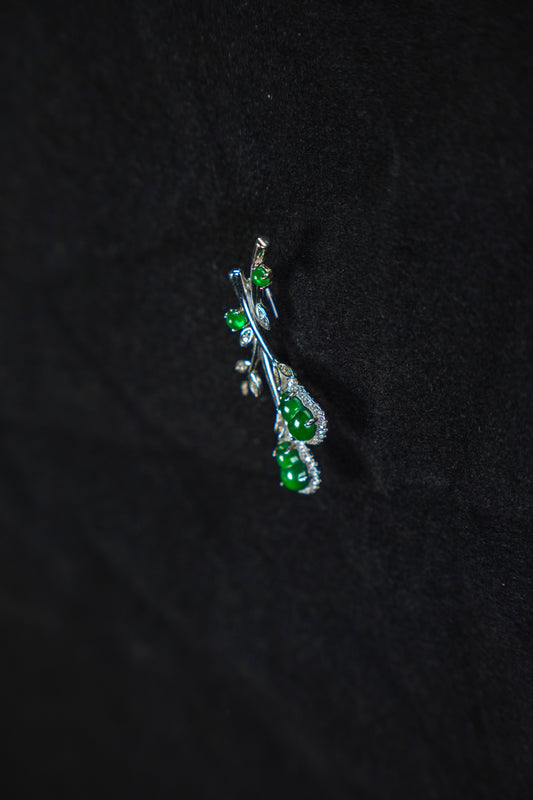 Silver pendant with green gemstones on a black background
