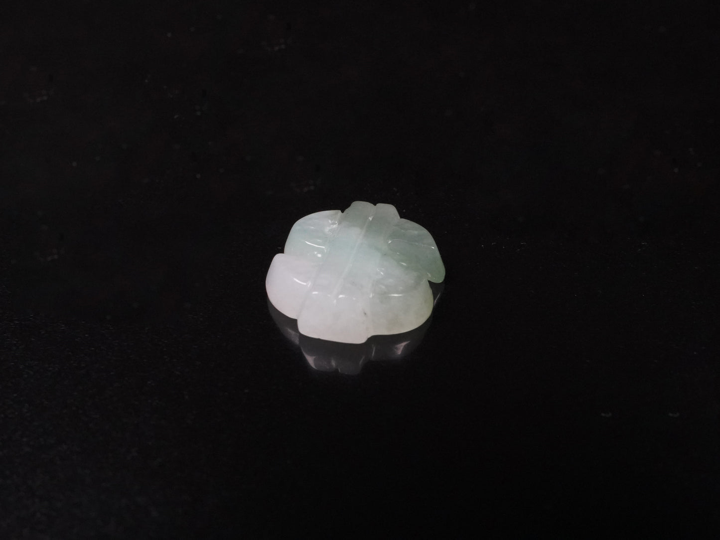 A soft gradient green white dollar symbol loose jadeite.