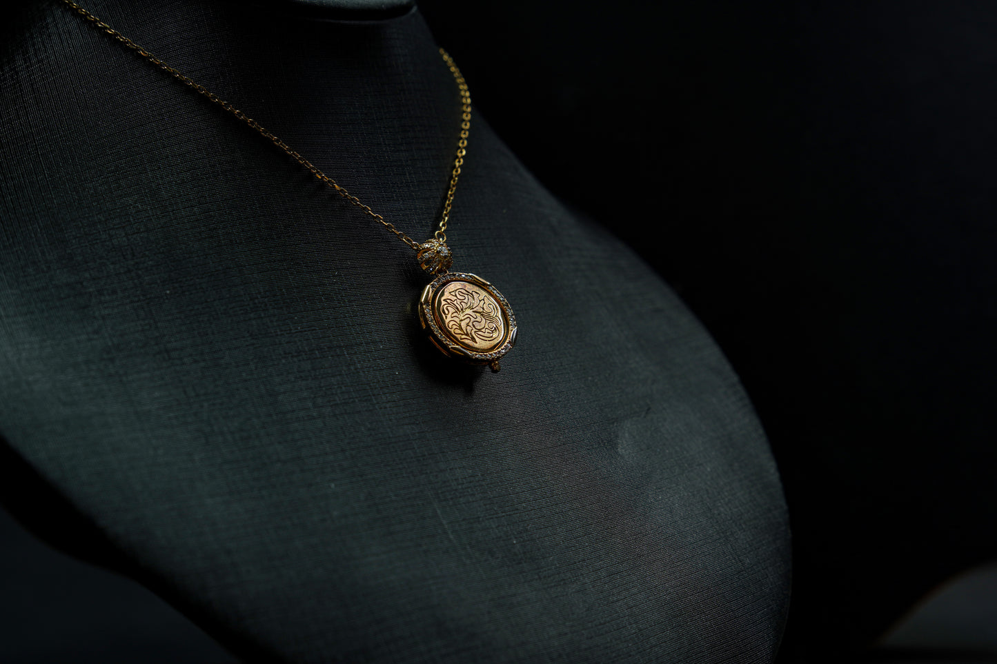 Gold necklace with a pendant on a dark fabric background