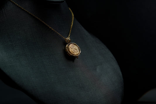 Gold necklace with a pendant on a dark fabric background