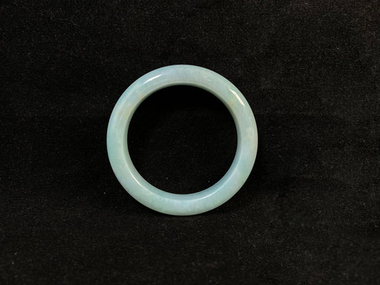 This bracelet showcases a pale green jade with a subtle purple hue.