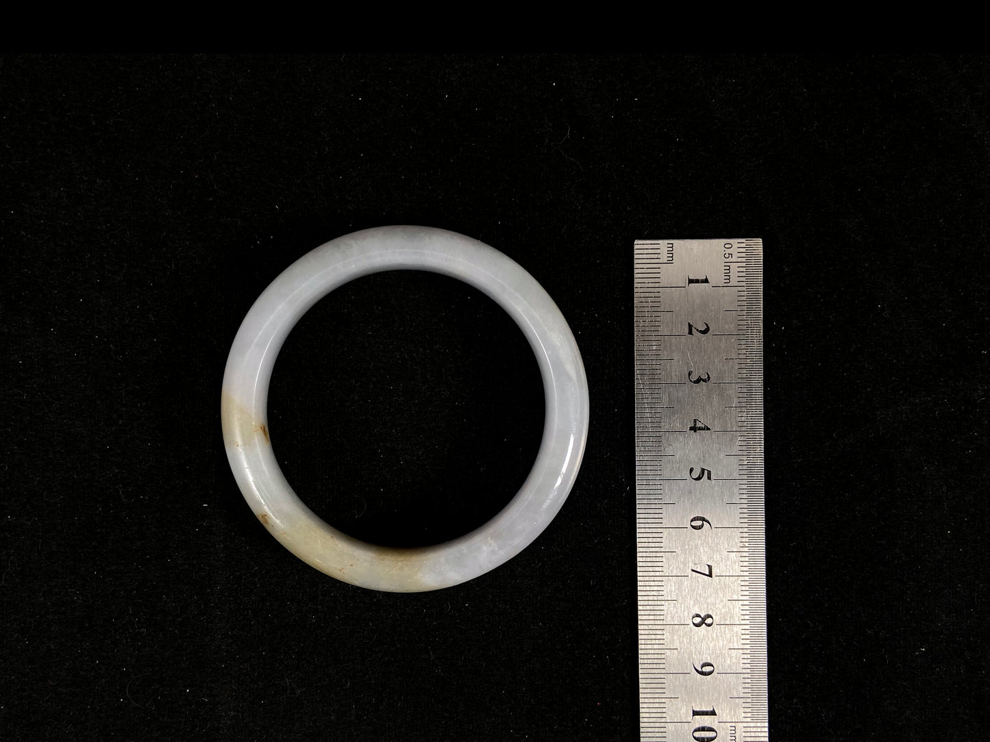 A creamy ivory jade bangle delicately kissed by two strokes of sunlit gold.