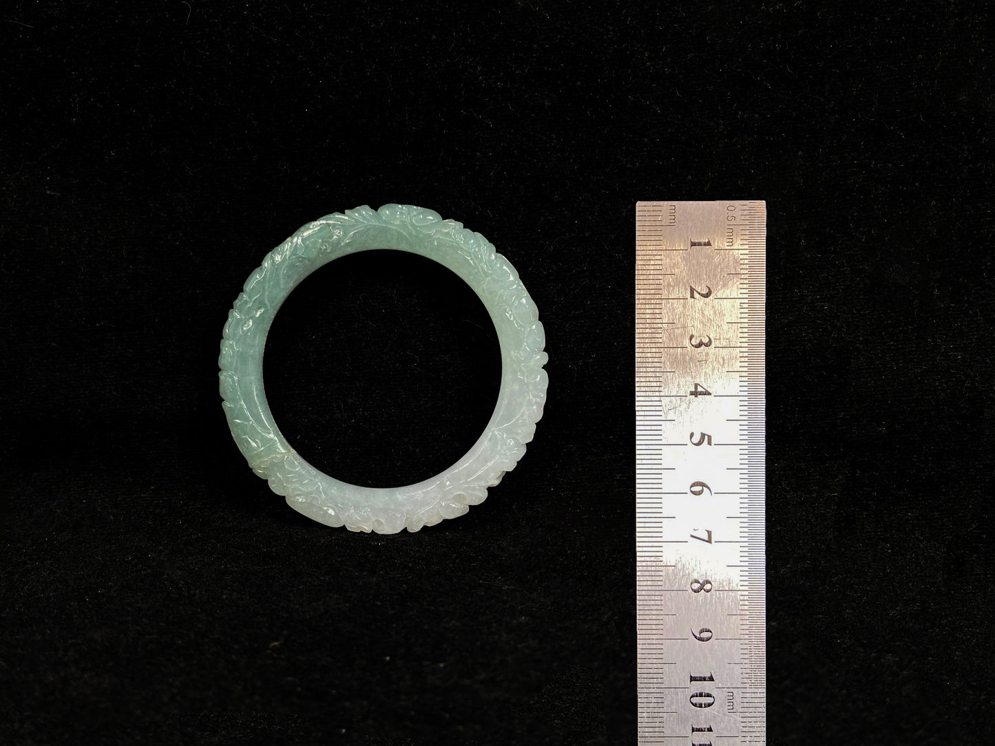 A carved jadeite bangle with half green and half white sections.