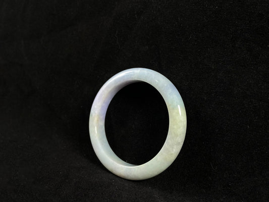 A lavender and green jade bangle sprinkled with sunlit gold specks.