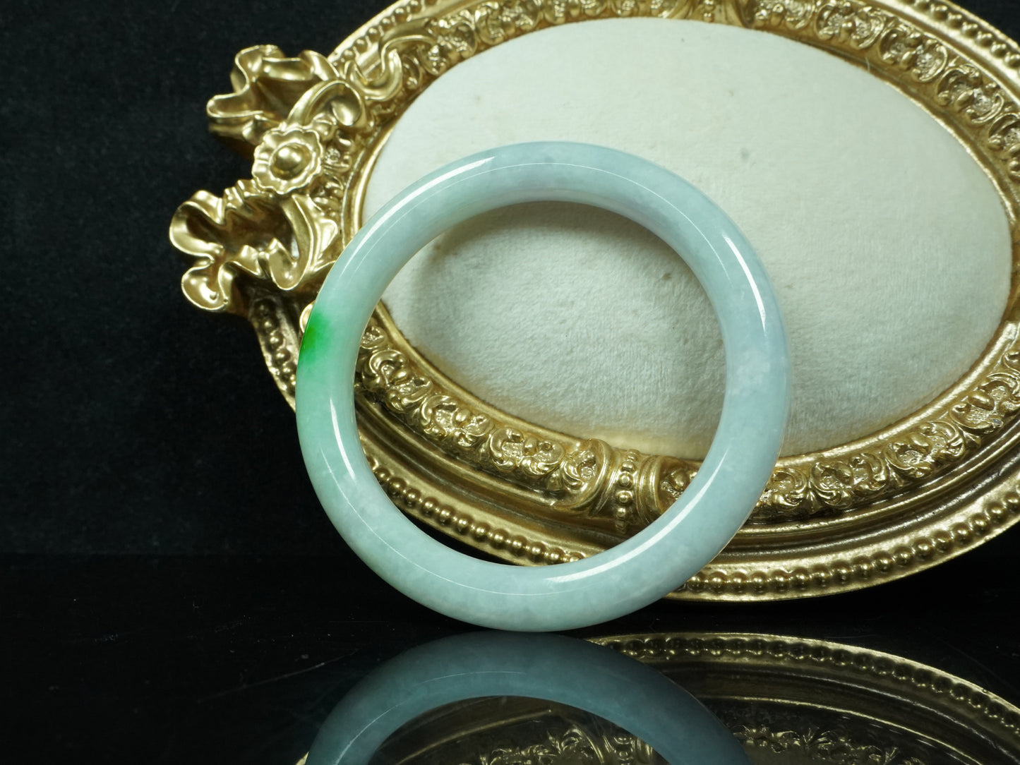 A milky white with delicate green accents jadeite bangle.