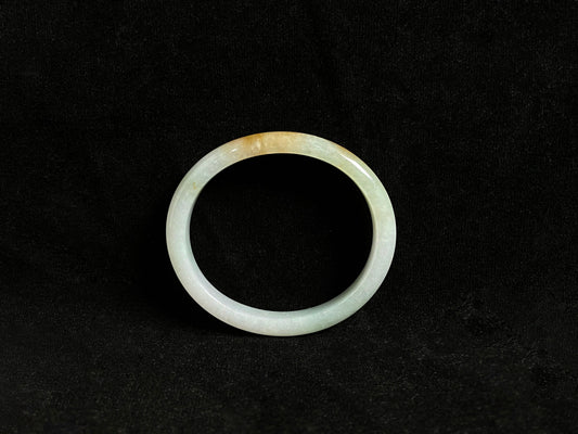 This jade bangle features a creamy white base adorned with delicate gold sprinkles, creating an elegant two tone effect.