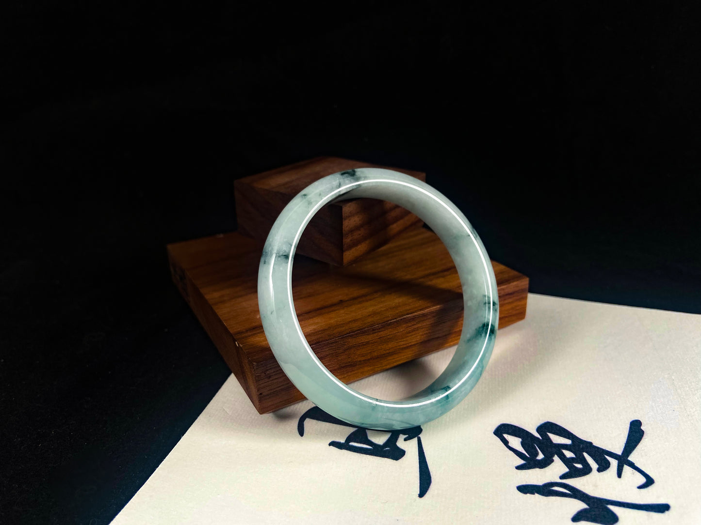 Silver ring on a wooden stand with a dark background