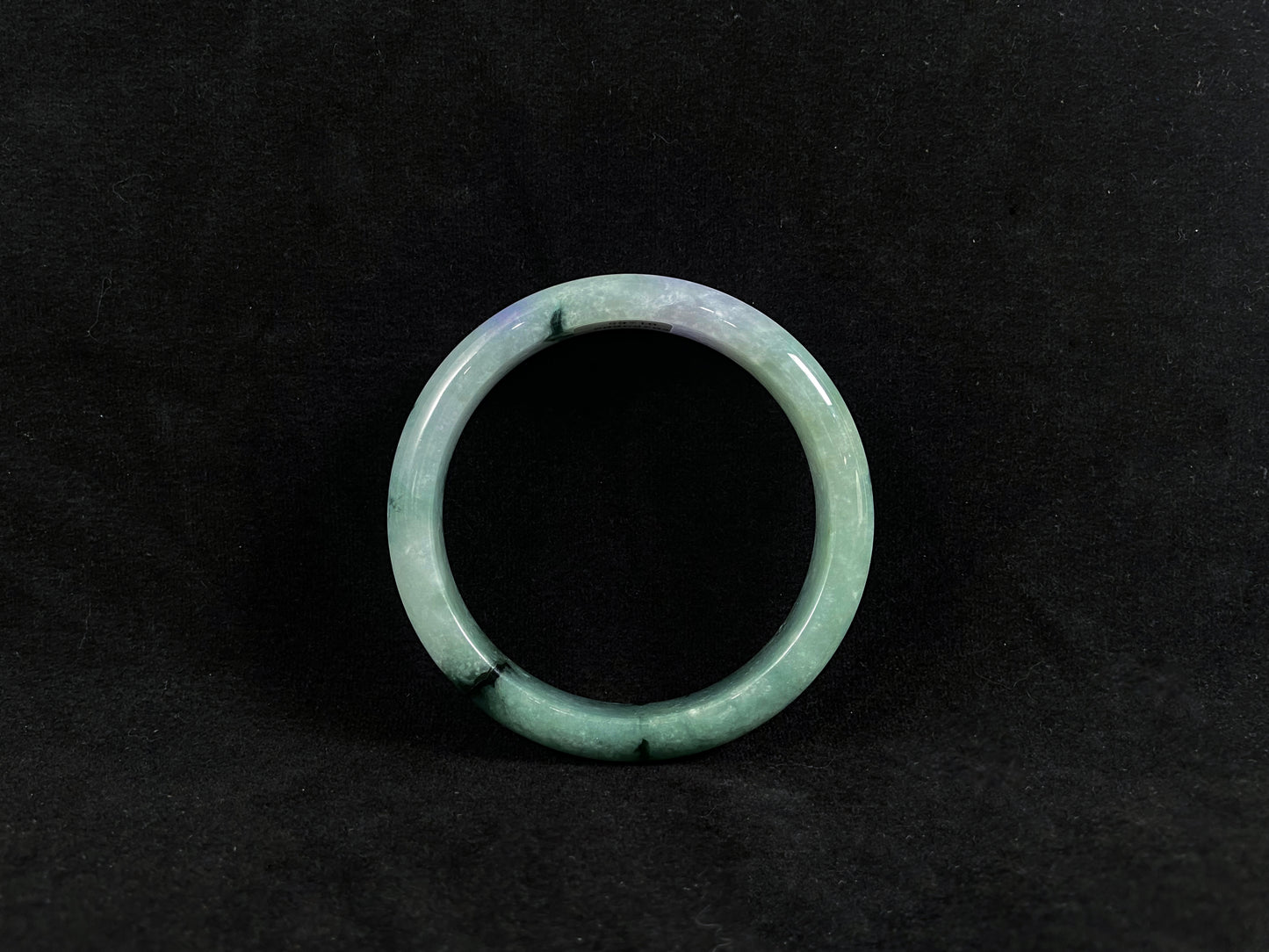 Green jade ring on a black background