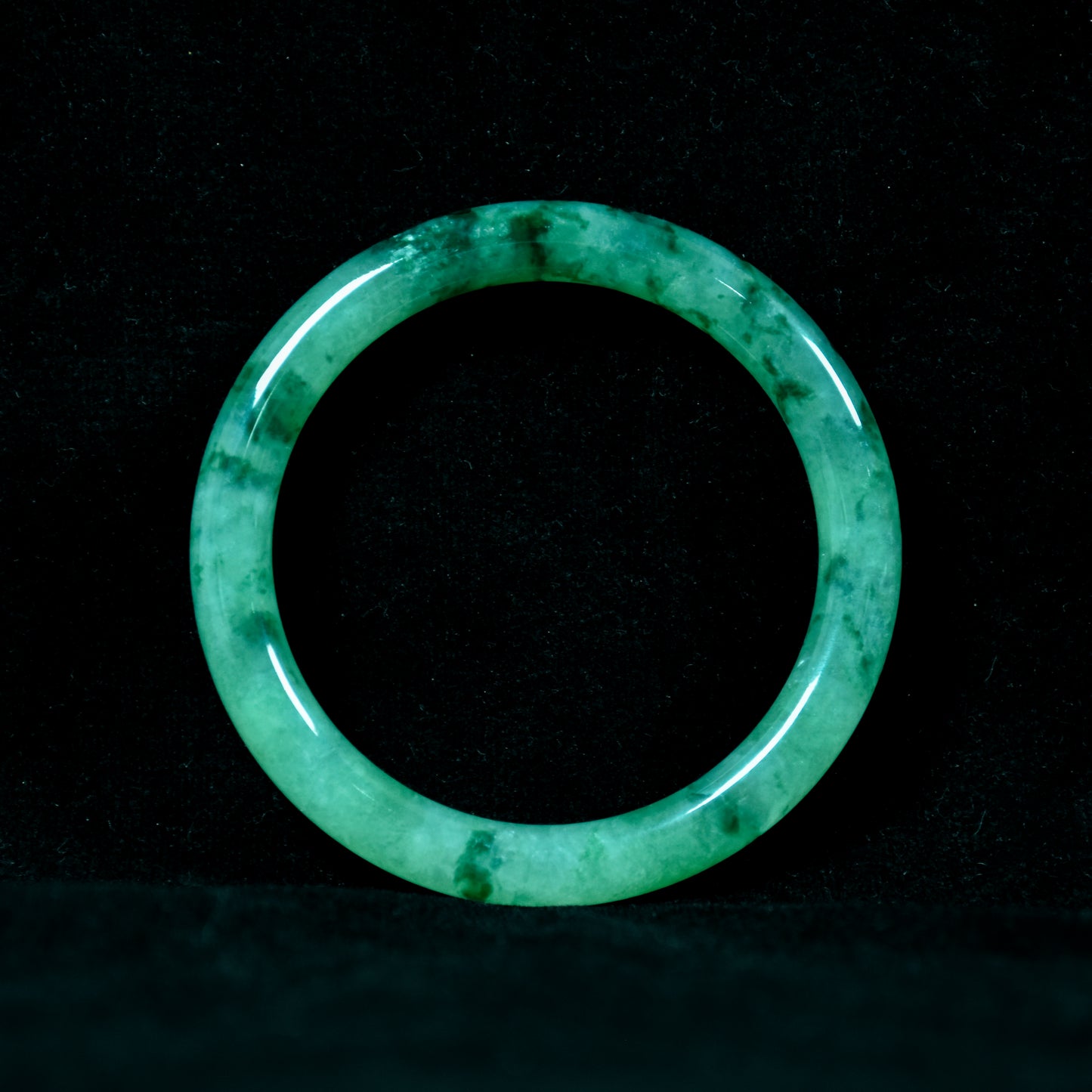 Green jade ring on a black background