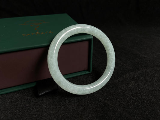 This delicate jade bangle features a pale green hue and slender circular profile, with finely crafted thin rods that create an elegant, youthful feminine aesthetic.