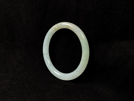 This jadeite bangle has a soft pale cyan base with cream undertones and faint gold streaks.