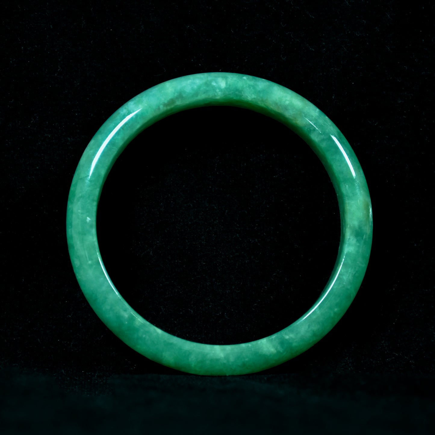 Green jade ring on a black background