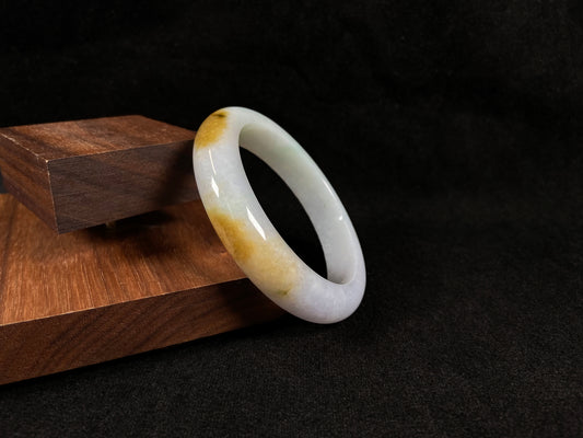 A white jadeite bangle featuring purple, gold, and light green tones.