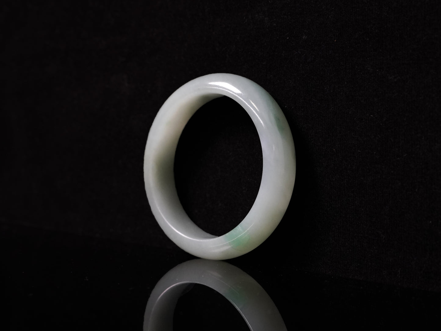 This bangle features a soft, translucent pale white base with a delicate swirl of light emerald green.