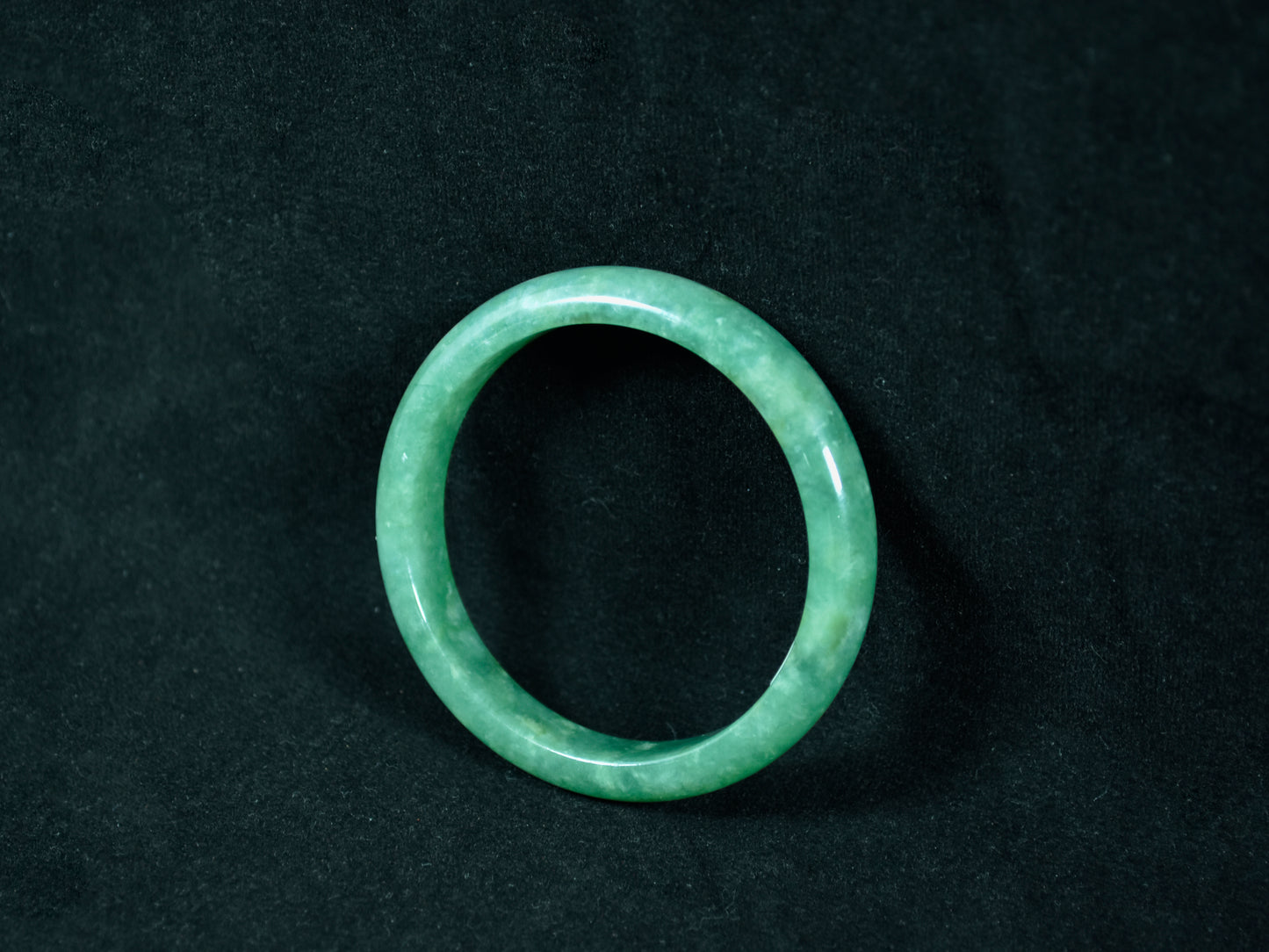 Green jade ring on a black background