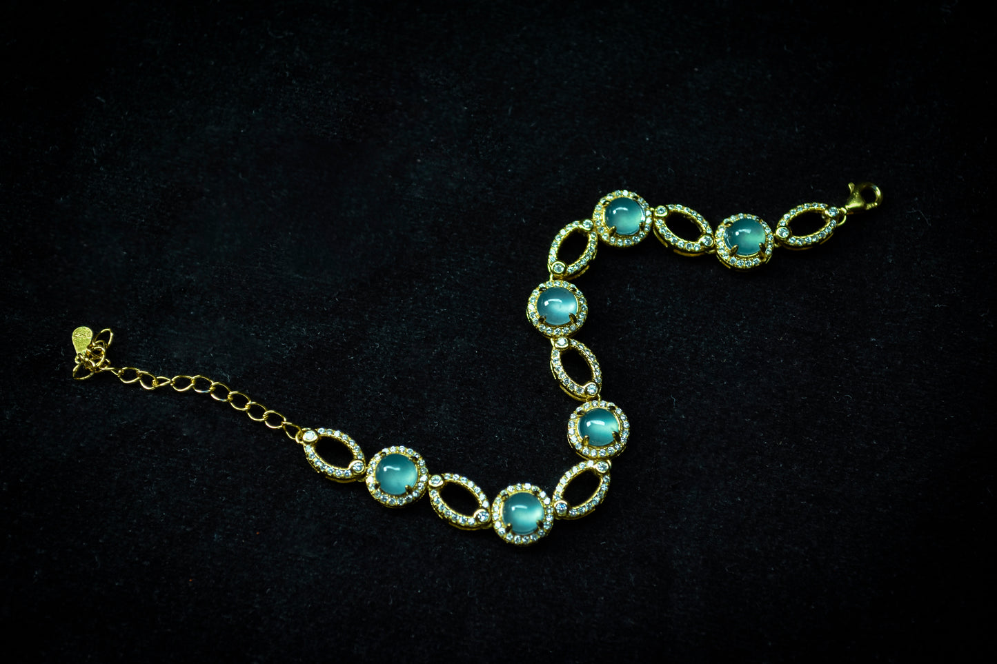 Gold bracelet with blue gemstones on a black background