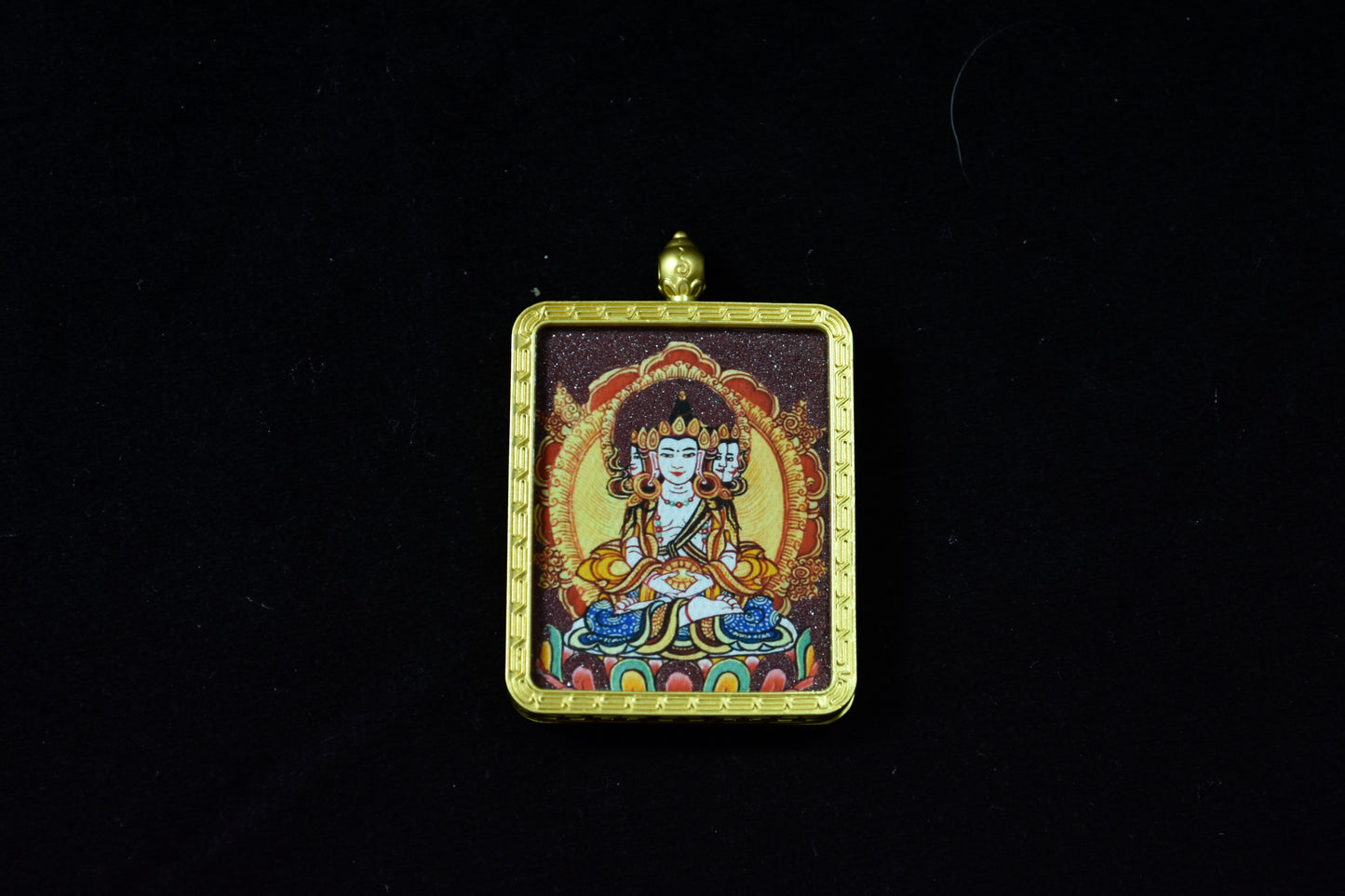 Decorative pendant with a figure in a gold frame on a black background