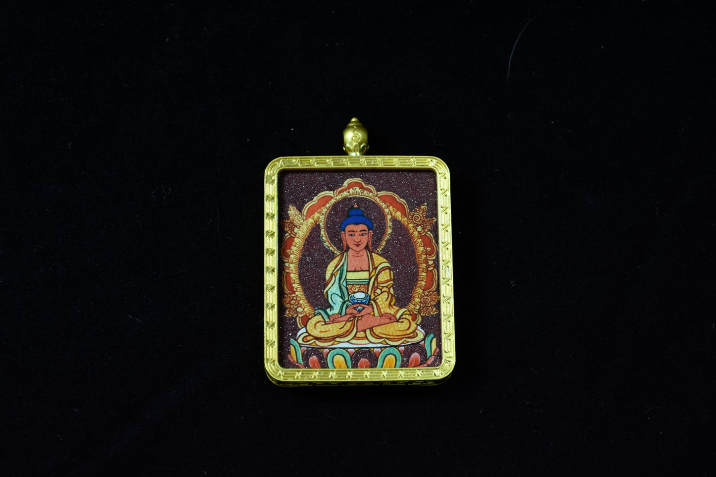 Decorative pendant with a figure in a meditative pose on a dark background