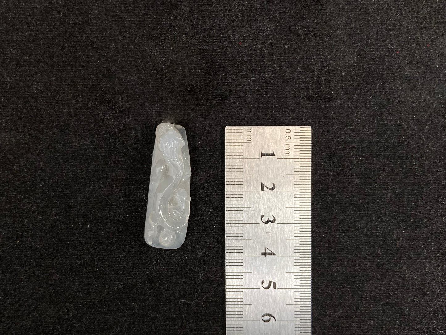 This jadeite is carved into a dragon motif in semi-transparent, milky white jade.