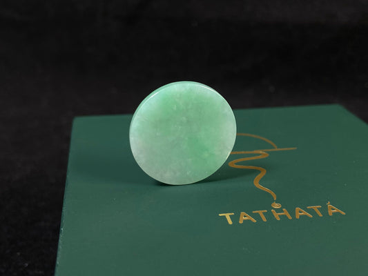 A delicate green jade stone with circular proportions.