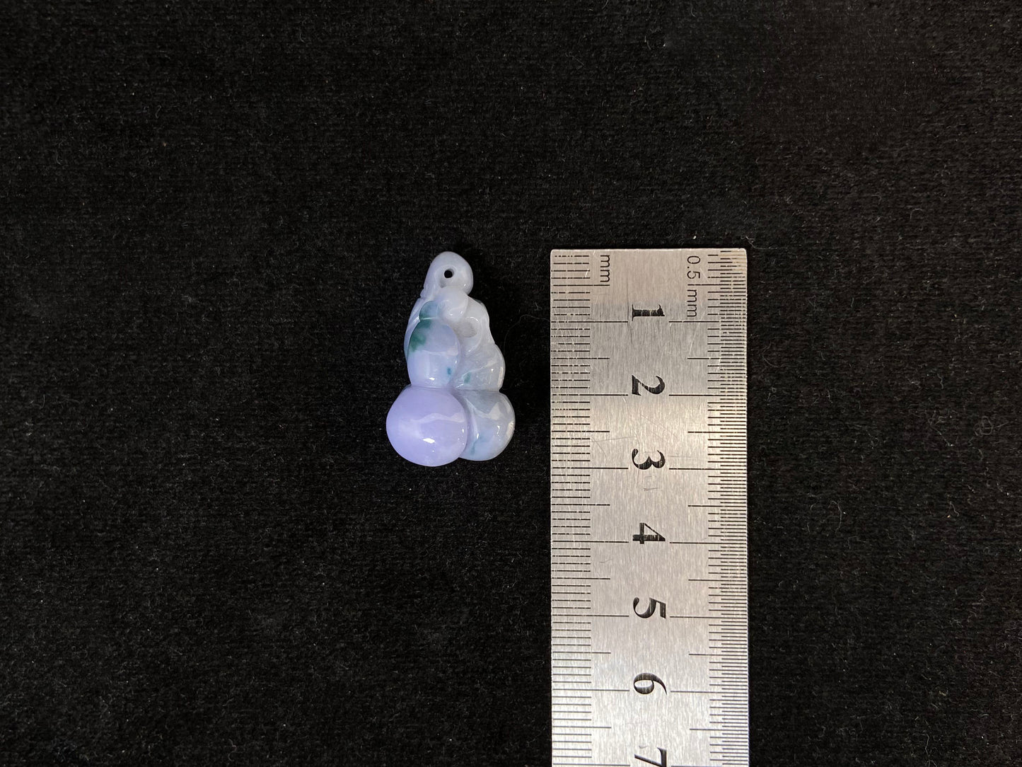 A violet jade carving of three entwined gourds, kissed by wisps of green.