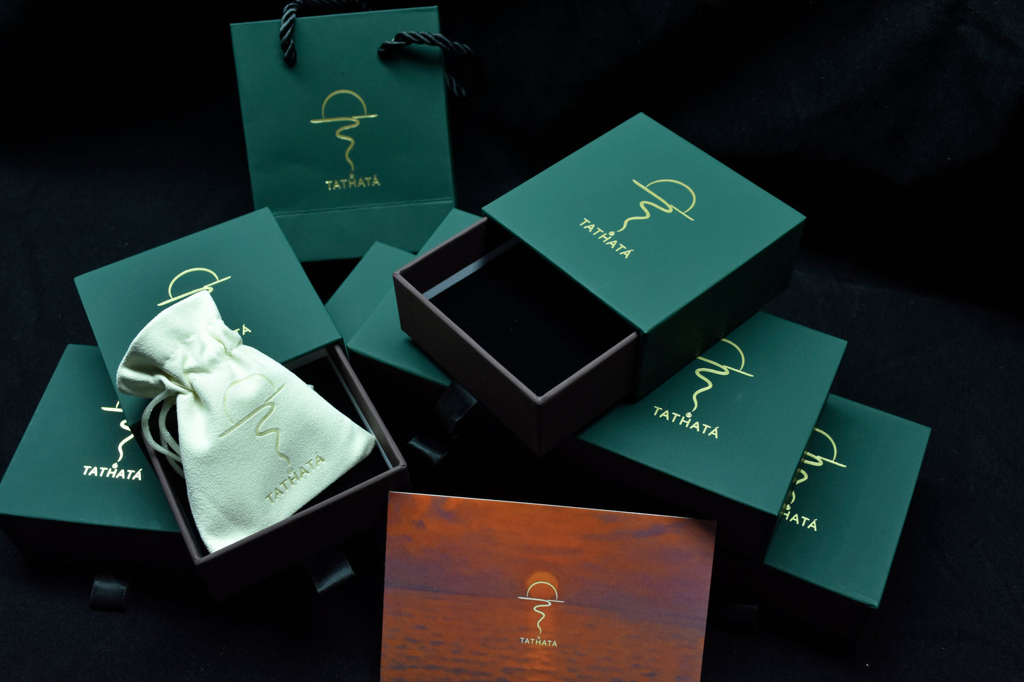 Tatiana jewelry packaging with green boxes and a black box on a dark background