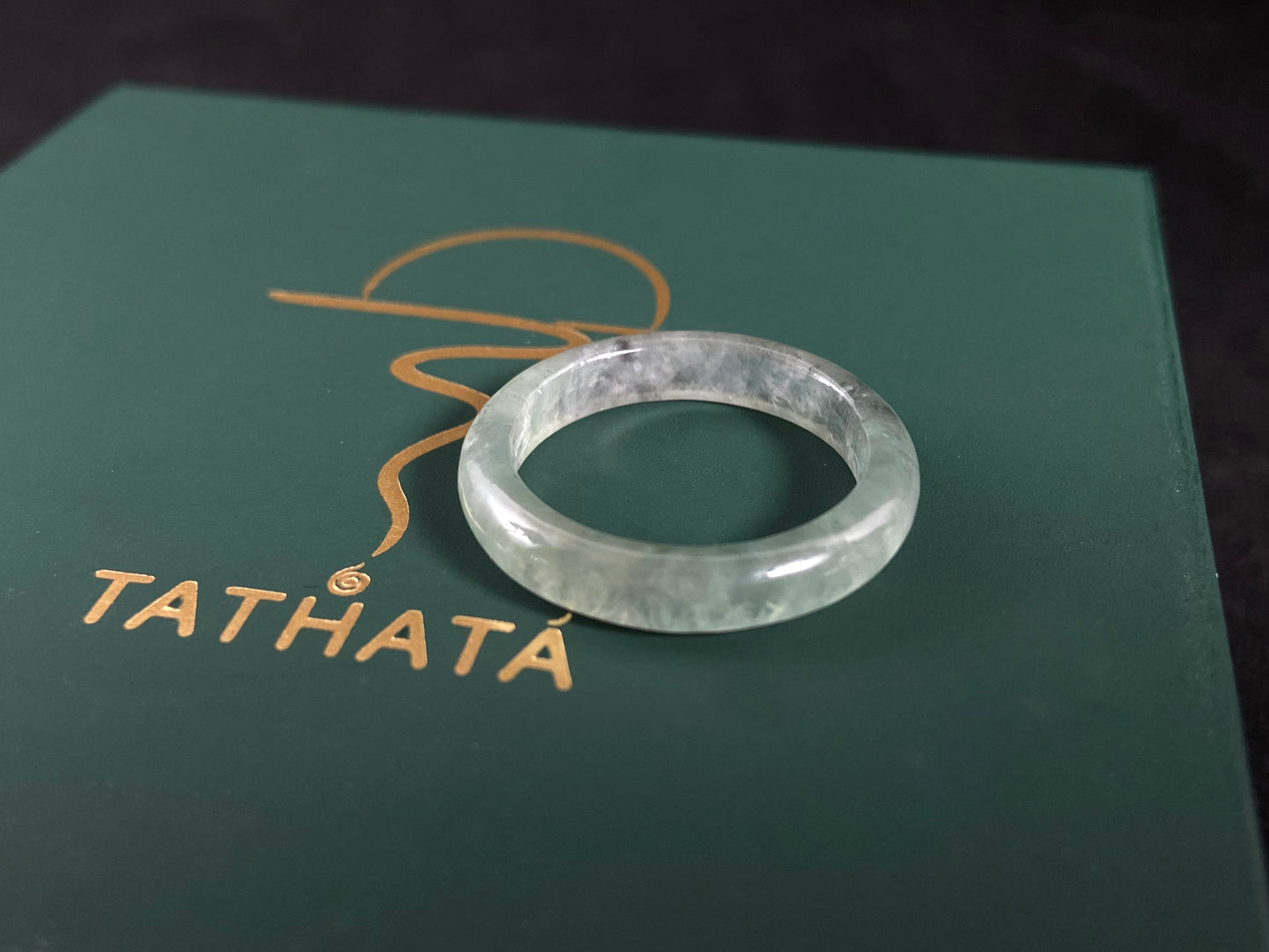Clear stone ring on a green box with 'Tathata' branding