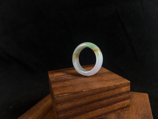 Green jade ring on a wooden stand with a black background