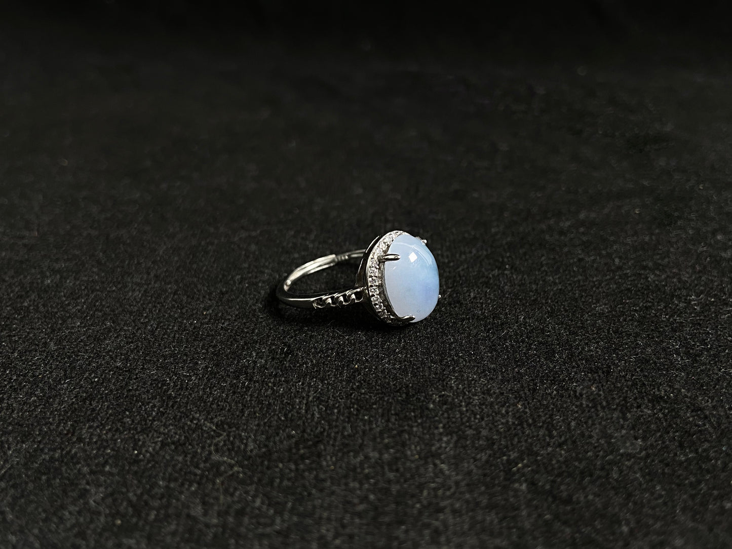 A frosty white jadeite ring featuring a deep green accent on its milky surface, crafted with prong setting to secure the circular gemstone.