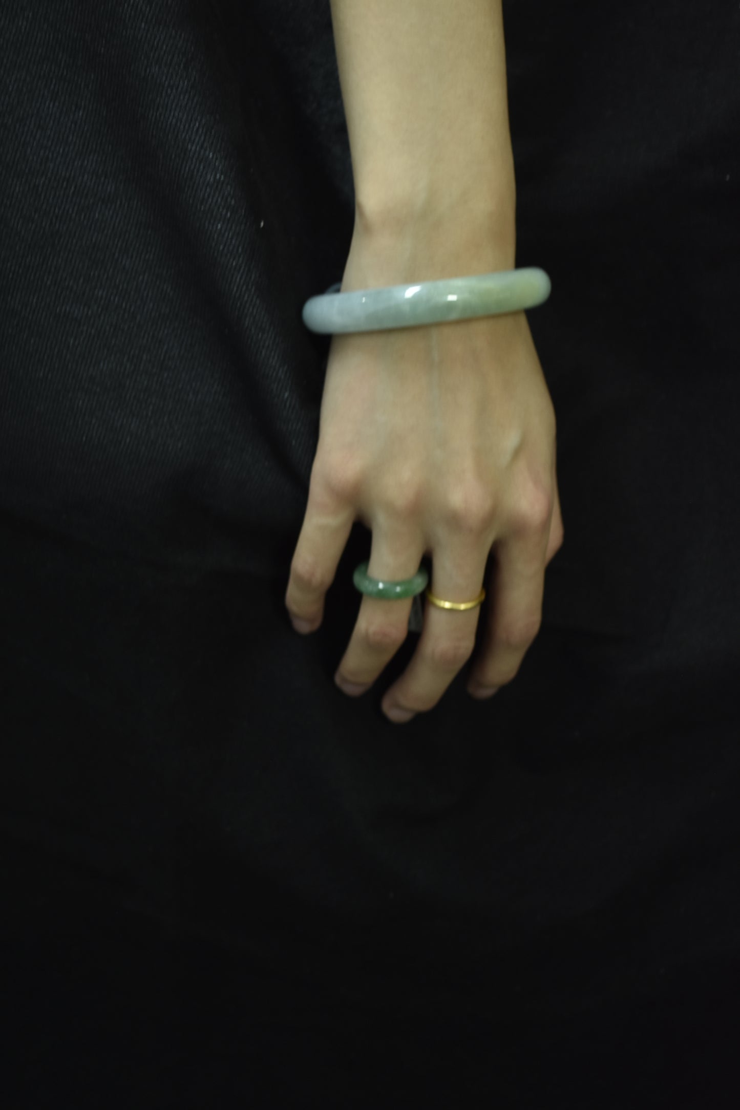 Model wearing a natural violet jadeite round bangle with gold rings, highlighting its elegance and translucency.