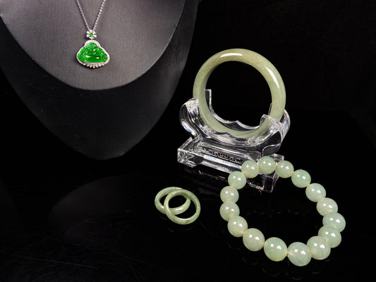 A set of four treasures of verdant glow Natural Burmese Jadeite. It includes a Buddha pendant, a round bangle, a beaded bracelet, and a plain band ring. 
