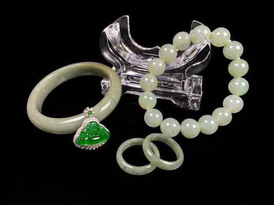 A set of four treasures of verdant glow Natural Burmese Jadeite. It includes a Buddha pendant, a round bangle, a beaded bracelet, and a plain band ring. 
