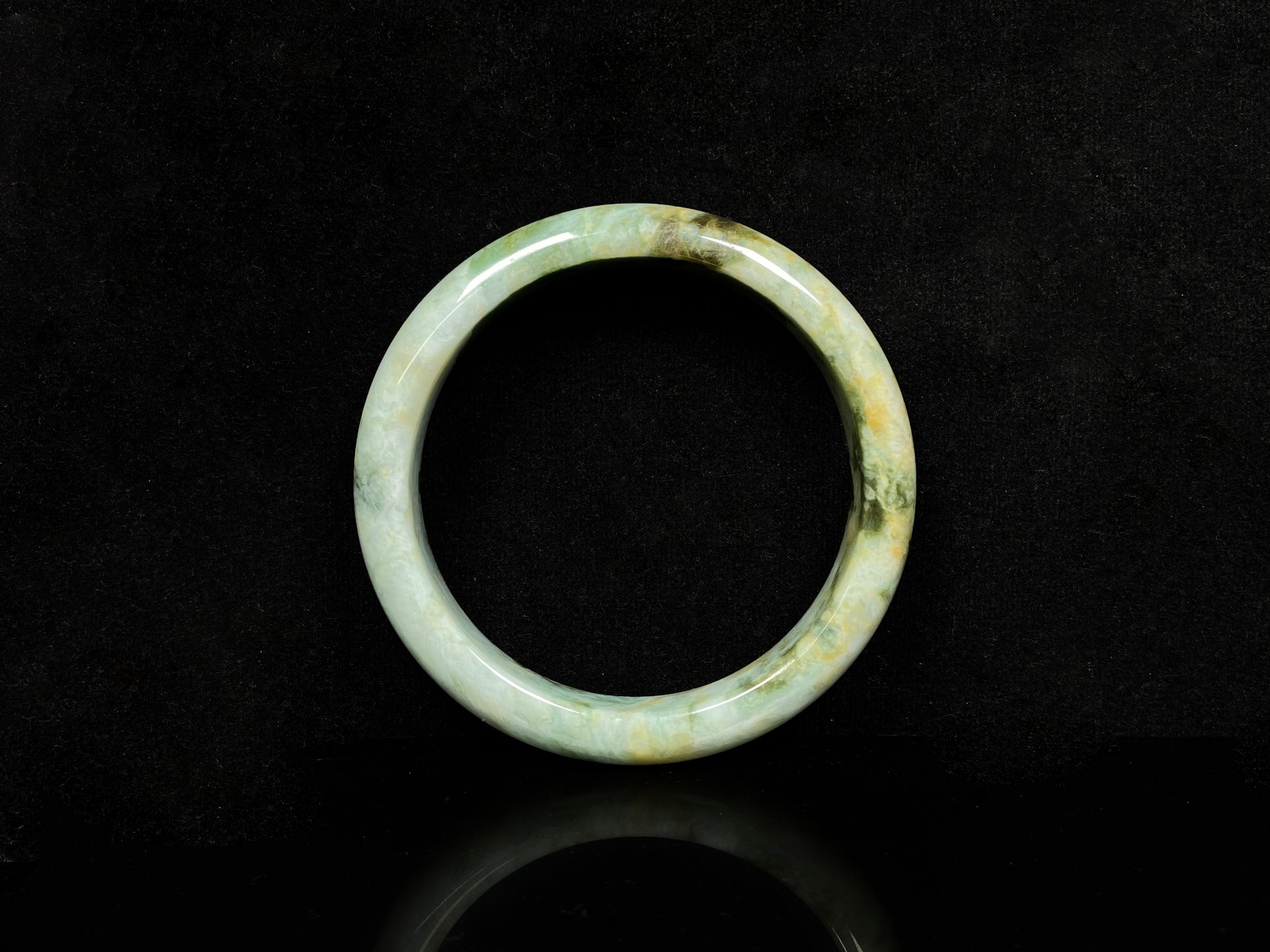 A mossy green with honeyed veins jadeite bangle.