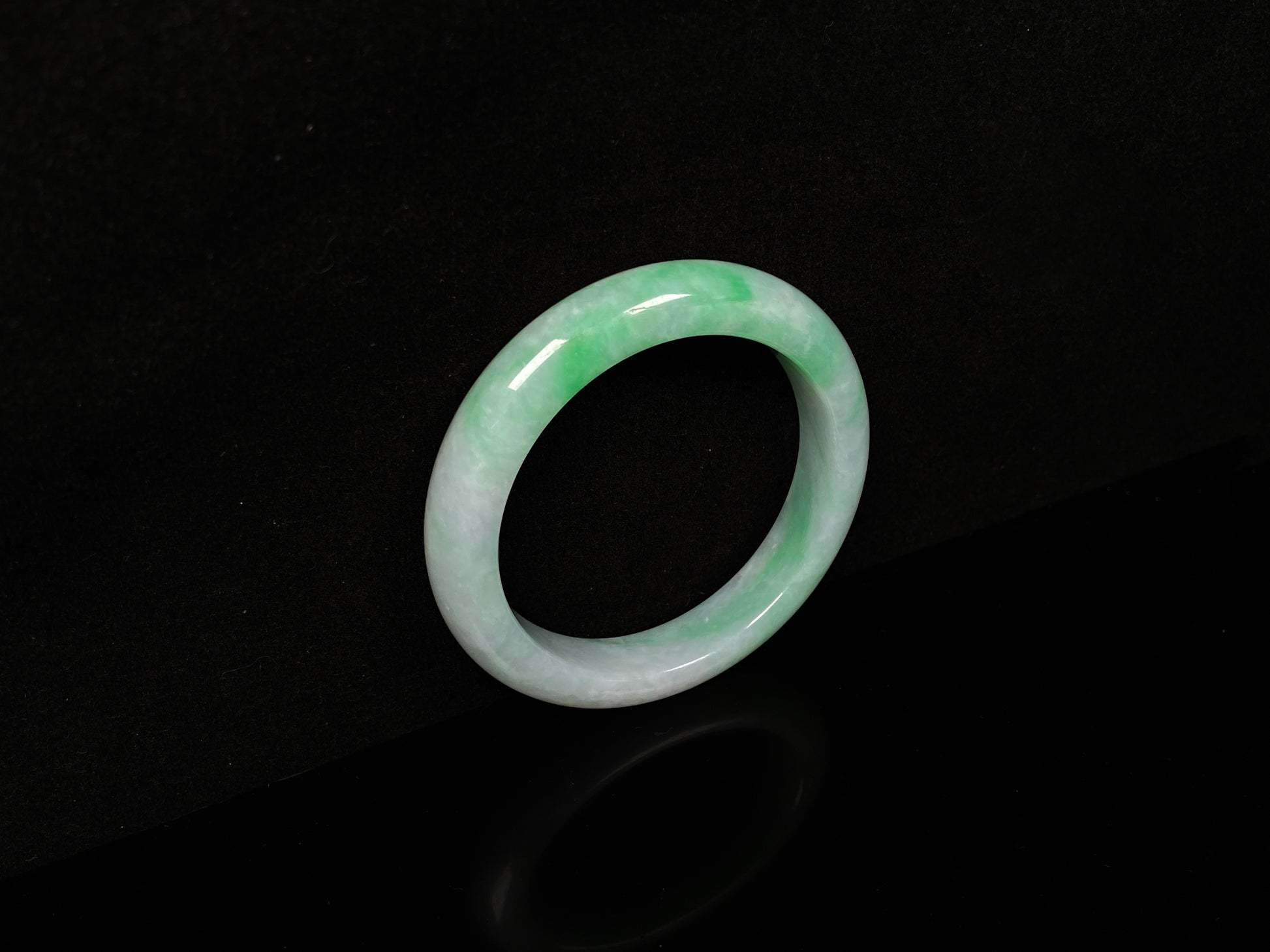 A white field with floating green hues jadeite bangle.