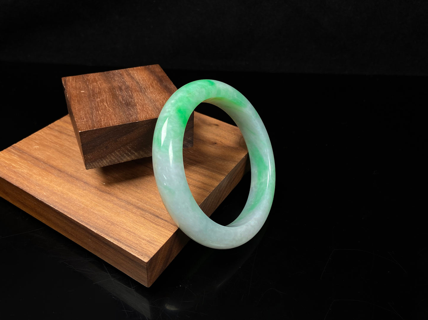 A white field with floating green hues jadeite bangle.