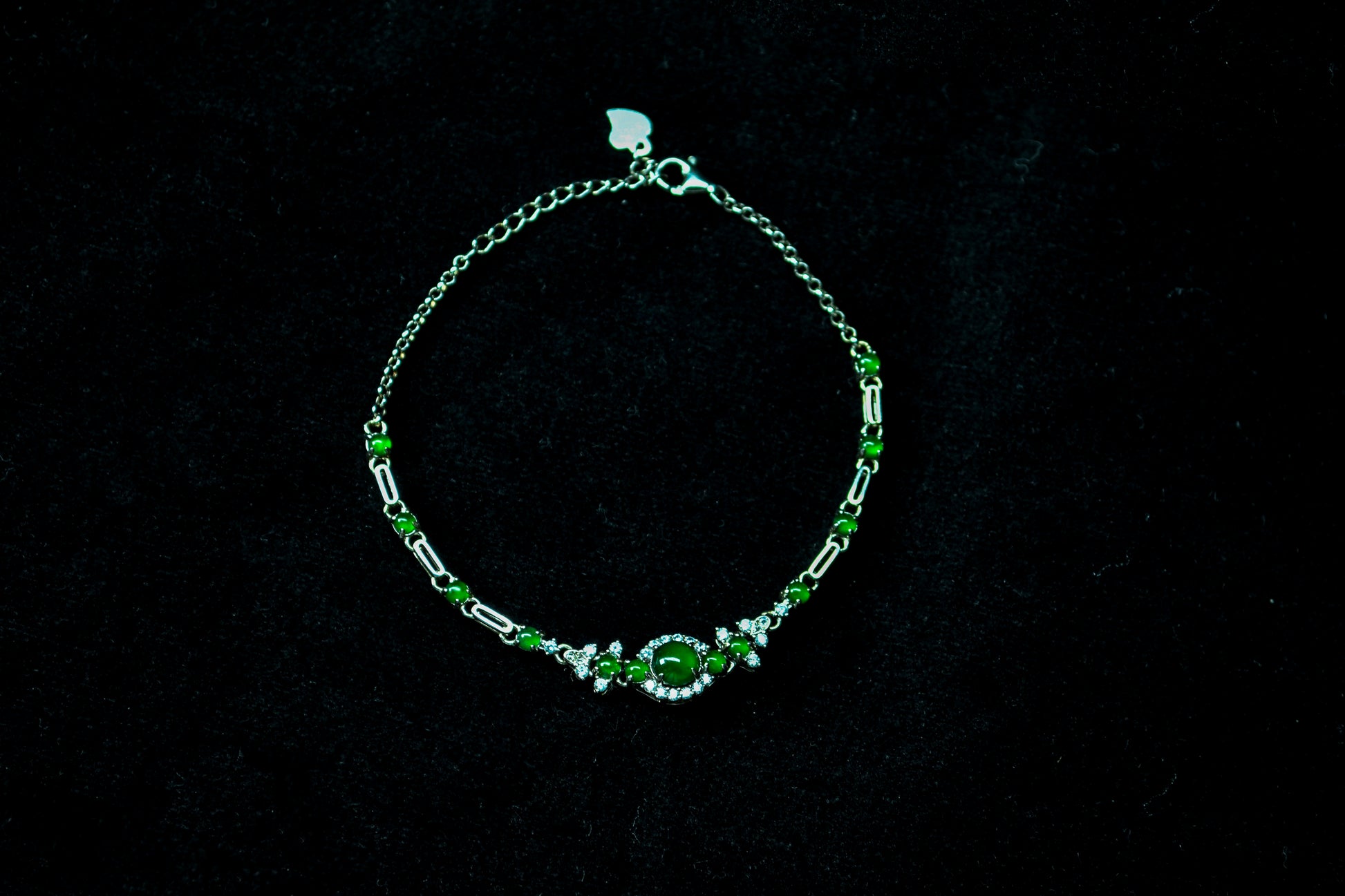 Silver bracelet with green gemstones on a black background