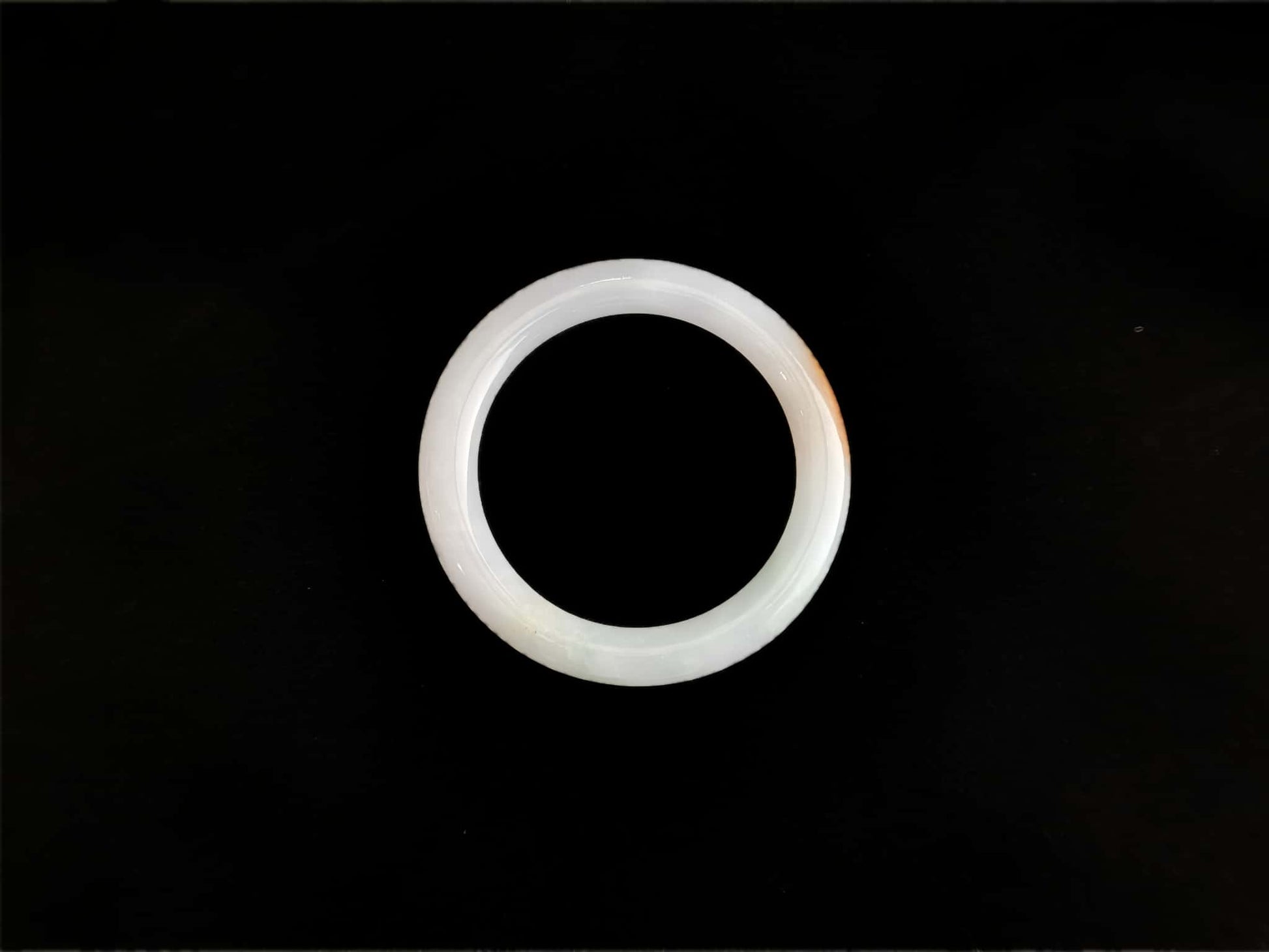 A pure white warm orange inlay jadeite bangle.