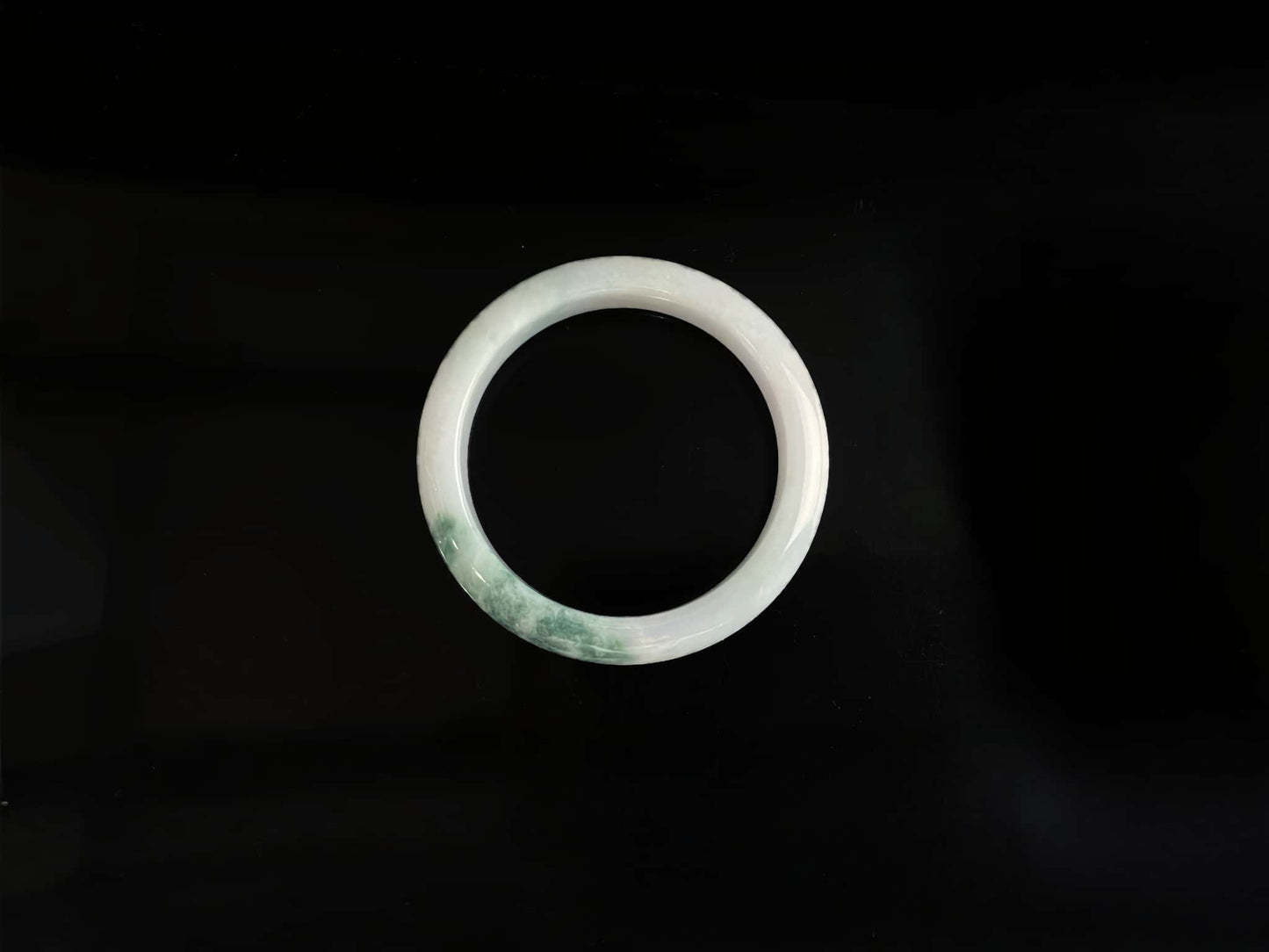 A snow white with green splash jadeite bangle.