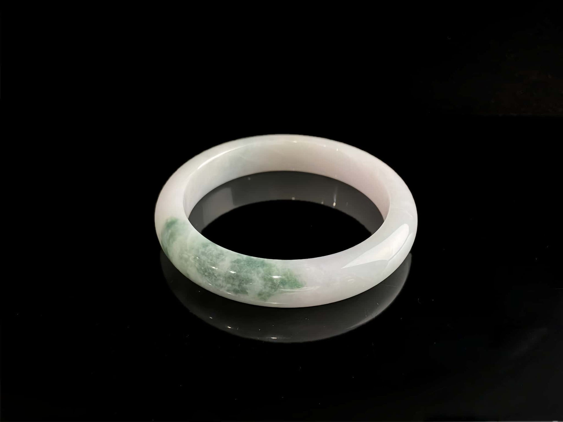 A snow white with green splash jadeite bangle.