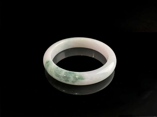 A snow white with green splash jadeite bangle.