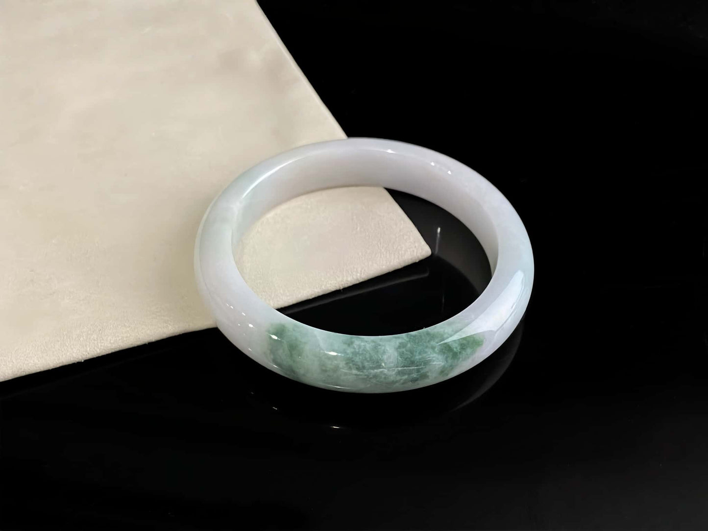 A snow white with green splash jadeite bangle.