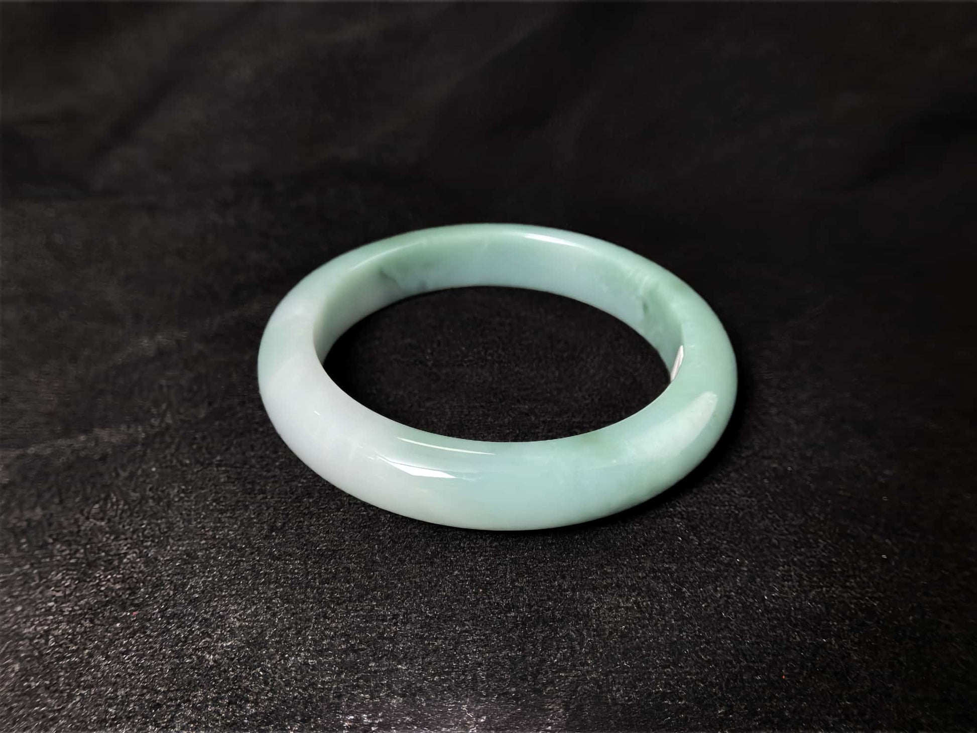 A white base mint green veil jadeite bangle.