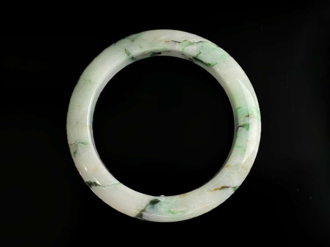A white base with multi-colored inclusions jadeite bangle.