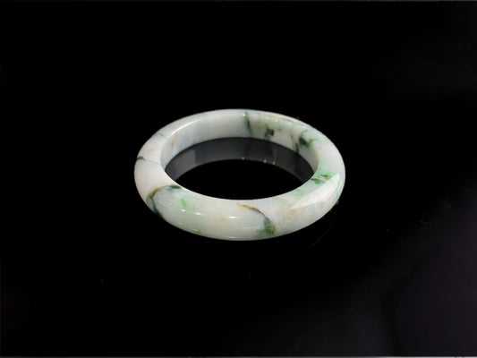 A white base with multi-colored inclusions jadeite bangle.