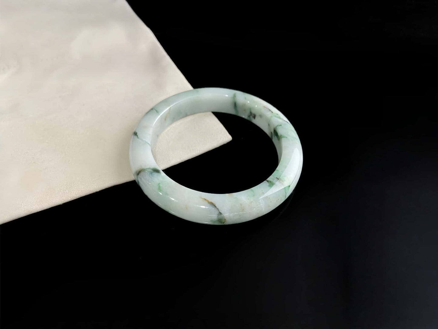 A white base with multi-colored inclusions jadeite bangle.