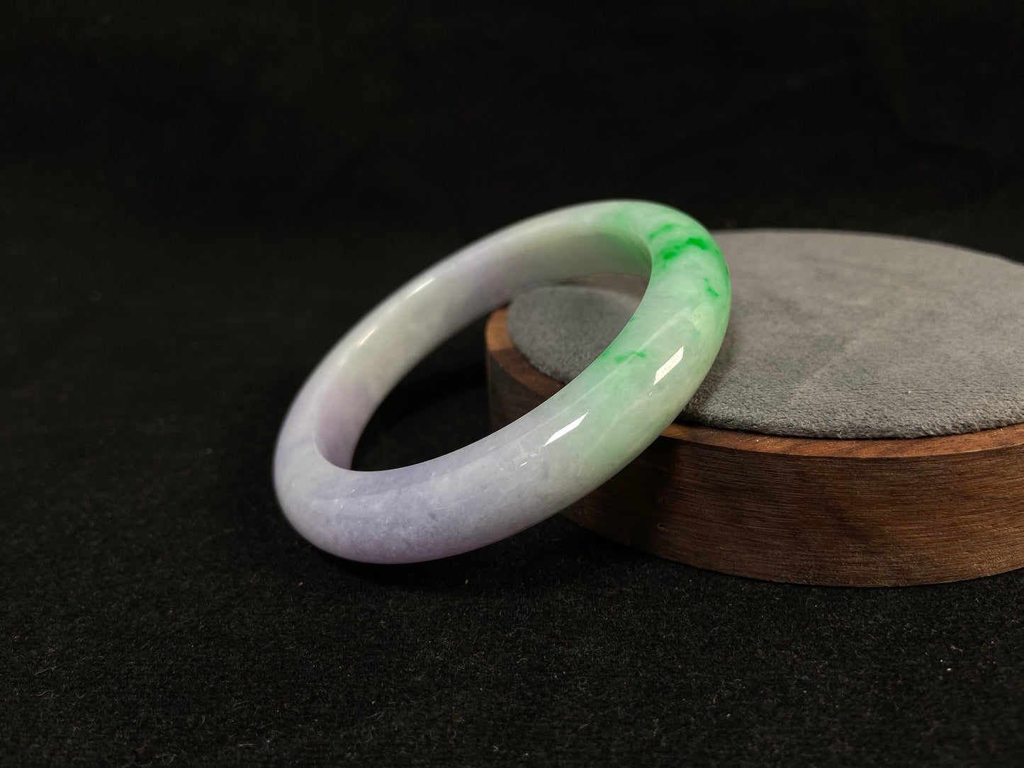 This natural jadeite bangle features a white base, elegantly divided into three sections: one in purple, one in green, and one in white with a subtle yellowish hue.